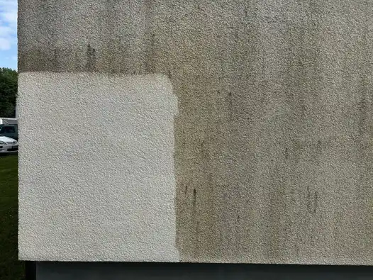 Verschmutzter Putz, ein Teil der Fläche ist bereits gereinigt