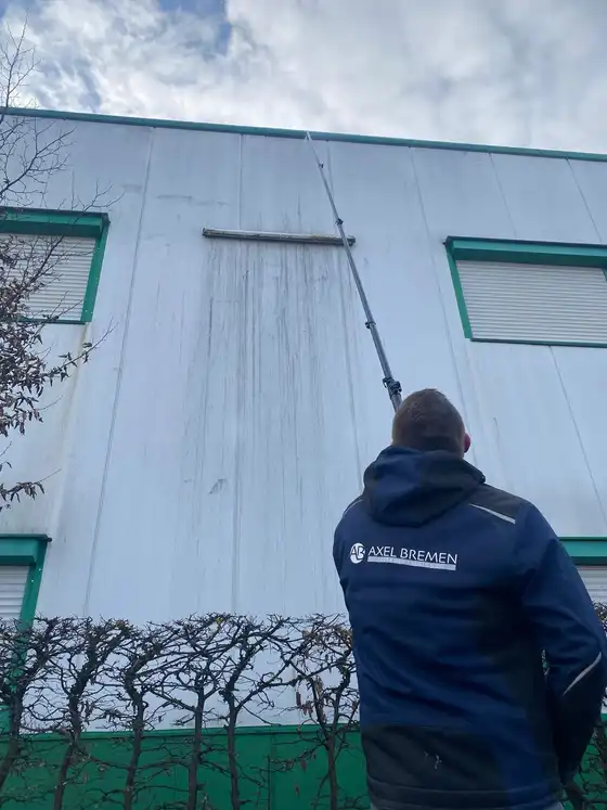 Mitarbeiter von Axel Bremen reinigt eine Hallenfassade mit der Teleskoplanze